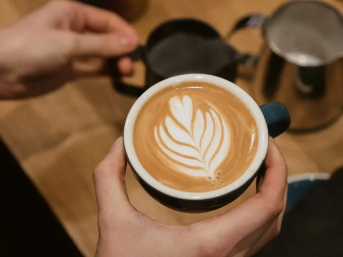 A person holding a latte cup with latte art in it